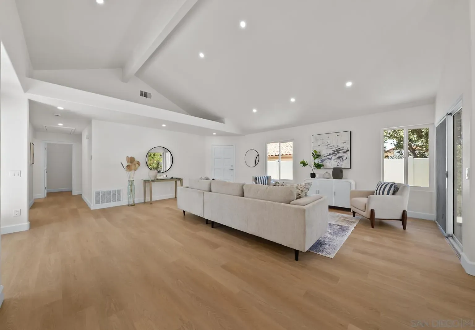 The front living room at 4742 Collinos Way, with vaulted ceilings, a long sectional, and an accent chair below abstract artwork