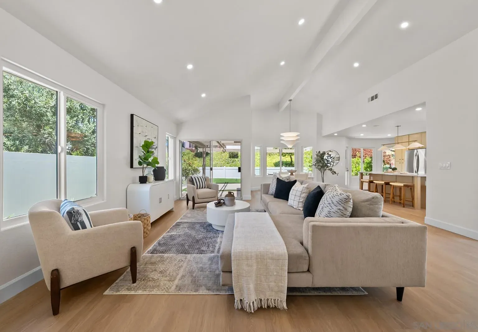 The great room at 4742 Collinos Way, with vaulted ceilings, a beige sectional, and sliding doors opening to the rear garden